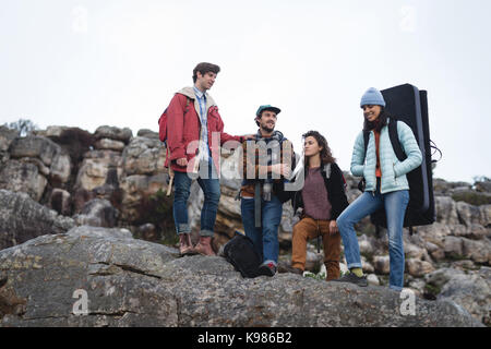 Friends standing on top of the cliff on a sunny day Stock Photo