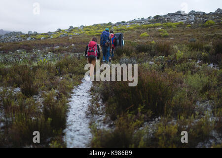 Rear view of friends with rucksack walking on path Stock Photo