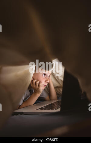 Cute boy using laptop in bedroom Stock Photo