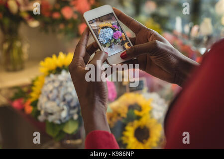Close-up of female florist taking photograph on mobile phone of flower bouquet Stock Photo