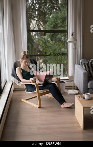 High angle view of young woman using technologies while sitting on chair at home Stock Photo