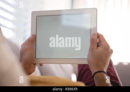 Man using digital tablet on sofa in living room at home Stock Photo