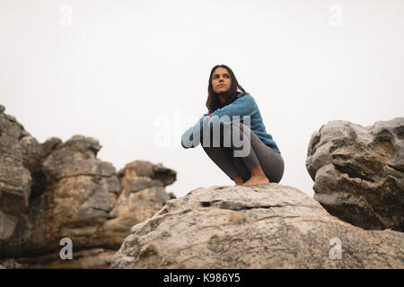 Thoughtful woman relaxing on rock during mountaineering Stock Photo