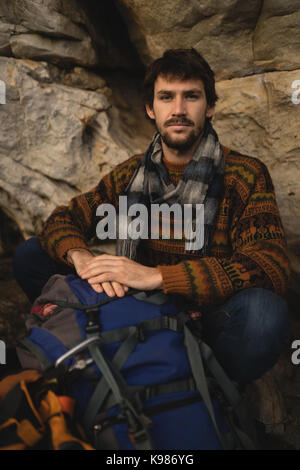 Portrait of confident man with rucksack relaxing on rock Stock Photo