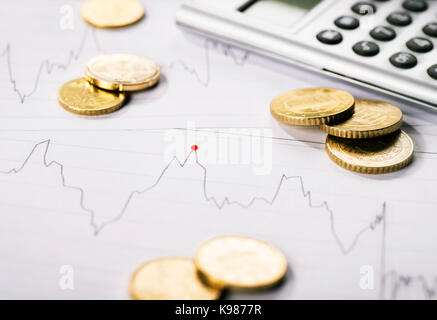 Diagram shows the trend of a course and is surrounded by coins and a calculator. Stock Photo