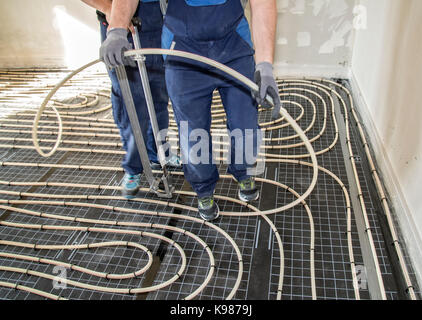 Craftsmen when laying pipes of underfloor heating Stock Photo