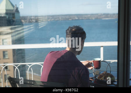 Man having cup of tea in balcony at home Stock Photo