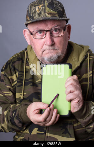 Senior man  with tablet studying news and presentation ideas. Project management and Corporate services. Tablet has empty green and copy space. Stock Photo