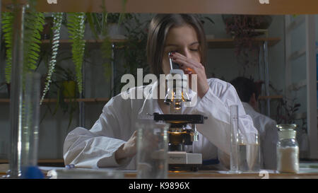 Young scientist looking through a microscope in a laboratory. Young scientist doing some research Stock Photo