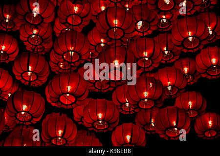 Red silk Chinese lanterns hanging in a large cluster during the Chinese Mid-Autumn Festival Stock Photo