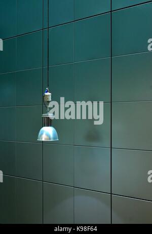 Pendant lamp suspended against a sheet aluminium wall Stock Photo