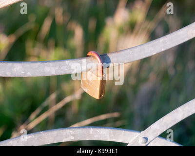 an old locked metal padlock outside on rail; England; Essex Stock Photo