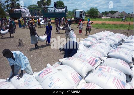 August 28, 2014 - Panweel Village - Kolnyang Payam, Bor County, South Sudan - Internally displaced refugees unload sacks of sorghum and split yellow peas from a truck. Thousands of South Sudanese became internally displaced refugees in Jonglei and Juba following the outbreak of fighting between forces loyal to South Sudan president Salvar Kiir and his ex-vice president Rick Machar in December 2013. To help displaced and conflict-affected households return home and start the recovery process aid organizations have engaged in emergency response activities such as providing emergency food rations Stock Photo