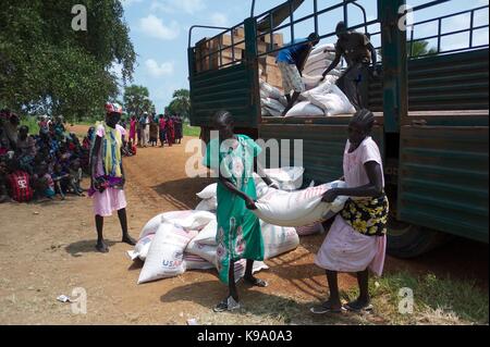 August 28, 2014 - Panweel Village - Kolnyang Payam, Bor County, South Sudan - Internally displaced refugees unload sacks of sorghum and split yellow peas from a truck. Thousands of South Sudanese became internally displaced refugees in Jonglei and Juba following the outbreak of fighting between forces loyal to South Sudan president Salvar Kiir and his ex-vice president Rick Machar in December 2013. To help displaced and conflict-affected households return home and start the recovery process aid organizations have engaged in emergency response activities such as providing emergency food rations Stock Photo