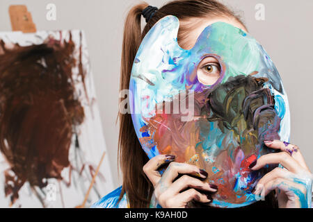 woman artistholds  palette with paints in front of face Stock Photo