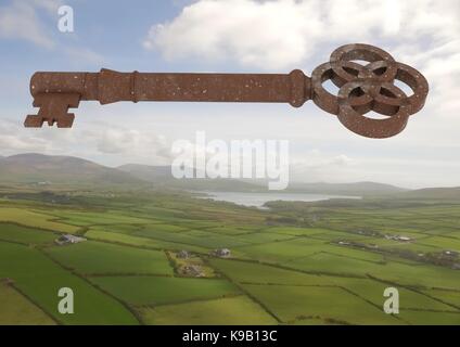 Digital composite of 3D Rustic Key floating over green landscape Stock Photo
