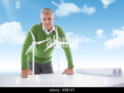 Digital composite of Confident business man  looking at  models of windmills on the table Stock Photo