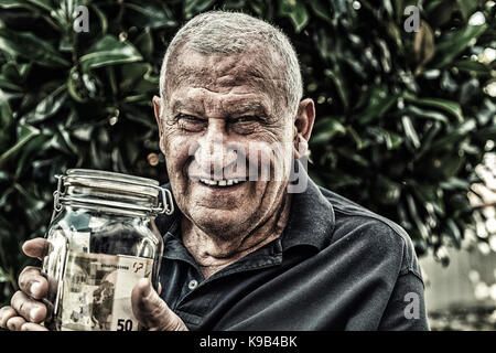 old man holding jar of money Stock Photo