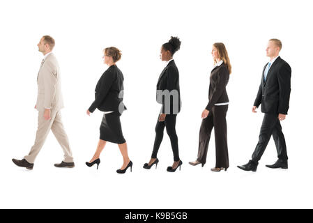 Full length side view of business team walking in row against white background Stock Photo