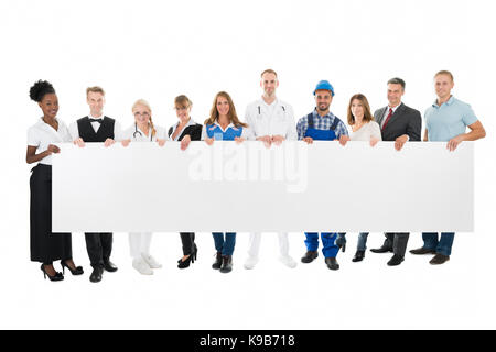 Group portrait of people with various occupations holding blank billboard against white background Stock Photo