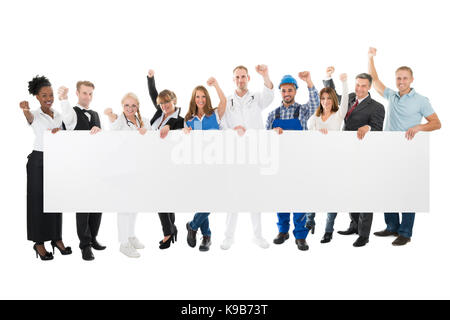 Group portrait of people with various occupations cheering while holding blank billboard against white background Stock Photo