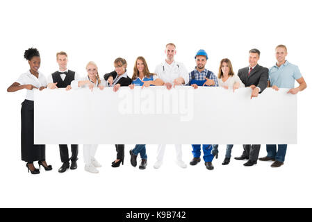 Group portrait of people with various occupations holding blank billboard against white background Stock Photo