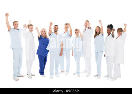 Full length portrait of multiethnic medical team standing with arms raised against white background Stock Photo