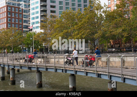 Hoboken, NJ USA -- SEptember 19, 2017 --Women pushing baby strollers along waterfront walkway in Hoboken. Editorial Use Only. Stock Photo