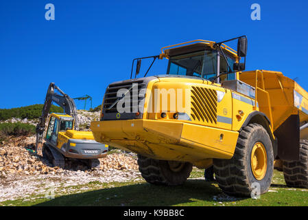 VOGEL MOUNTAIN, SLOVENIA - AUGUST 30, 2017: Construction machinery for crushing stone, Volvo bulldozer and large truck dumper working on mountain slop Stock Photo