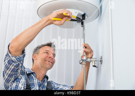 Portrait Of Happy Male Plumber Repairing Electric Boiler Stock Photo