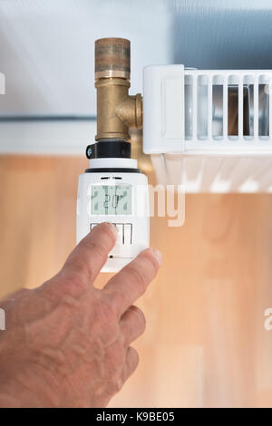 Close-up Of A Person's Hand Adjusting Temperature On Thermostat Stock Photo