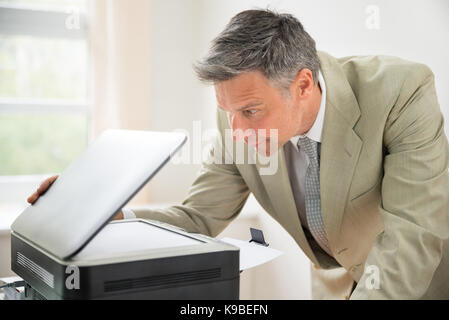 Close-up Of Mid-adult Businessman In Office Looking At Photocopy Machine Stock Photo