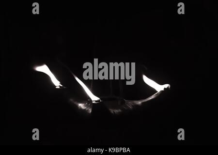 Three flames coming out of a clay oil lamp, in the dark. The lamp is suspended by a metal chain. Shot in Malta Stock Photo