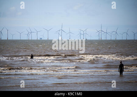 anthony gormleys another place on Crosby beach part of the crosby coastal park liverpool with wind farm in the background Stock Photo