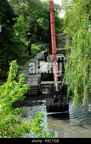 Dredging equipment clearing bottom silt out of river channel. Stock Photo