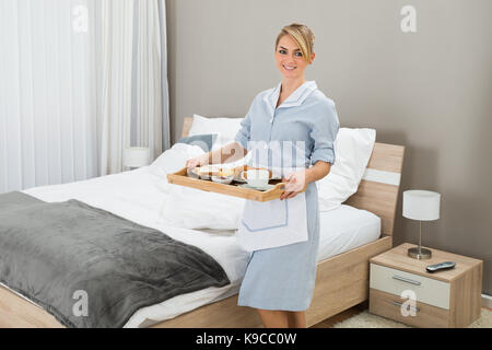 Happy Maid Carrying Breakfast Tray In Hotel Room Stock Photo