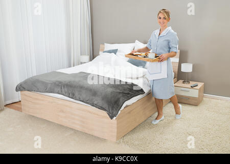 Happy Maid Carrying Breakfast Tray In Hotel Room Stock Photo
