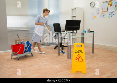 Young Maid Cleaning Floor With Mop In Office Stock Photo