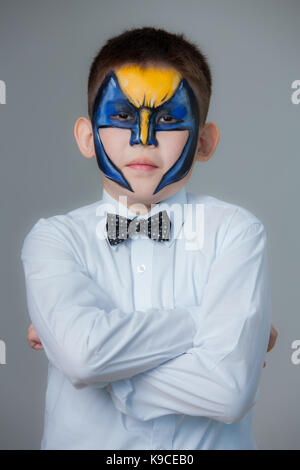 little boy painted like Batman on a gray background. face painting Stock Photo