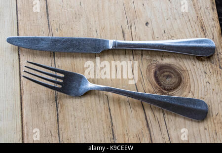 Detail of a Knife and Fork on an Old Rustic Oak Table, Ready for a Meal. Stock Photo