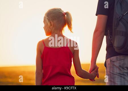 Father holding hand of daughter and walking on sand dune in desert ...