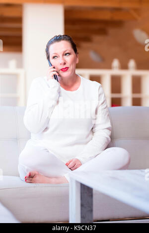 Portrait of a middle aged woman talking on the phone in a wooden Attic apartment. Stock Photo