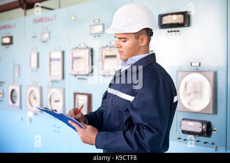 Portrait of young engineer taking notes at control room Stock Photo