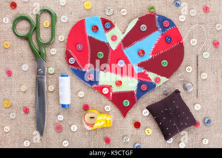 Sewing accessories and fabric scraps heart on fabric texture background . Valentine's Day Stock Photo