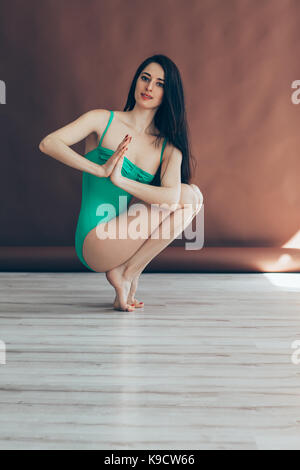 Young beautiful woman doing yoga asana tiptoe pose prapadasana variation on studio Stock Photo