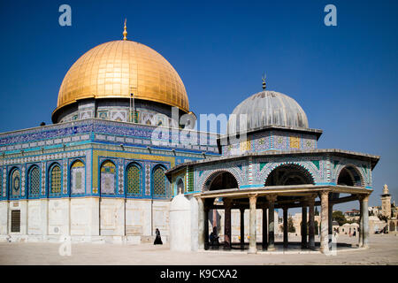 A street photography view of the Dome of Rock in Jerusalem, with a veiled woman passing by and showing the proportion of the site. Stock Photo