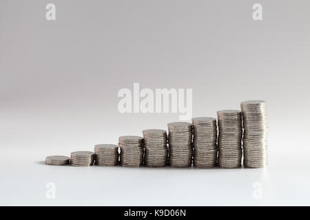 stacks of coins in ascending numbers from left to right symbolizing growing or increasing wealth, investments, savings, riches or general improvement Stock Photo