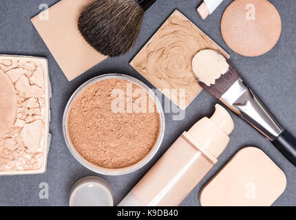 Makeup products and accessories to even out skin tone and complexion on gray textured surface Stock Photo