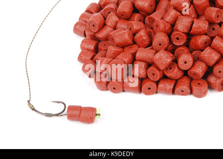 Fishing bait with hook and red pre-drilled halibut pellets for carp fishing isolated on white background with soft shadow Stock Photo