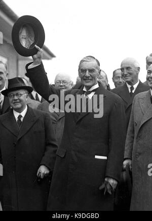 British prime minister Neville Chamberlain after returning from his summit meeting with the German Chancellor Adolf Hitler in Munich. Prime Minster Chamberlain returned with the paper signed by Hitler and himself sticking out of his pocket after declaring to the waiting crowd ' Peace in our time ' 3rd October 1938. With him is Sir Kingsley Wood Stock Photo